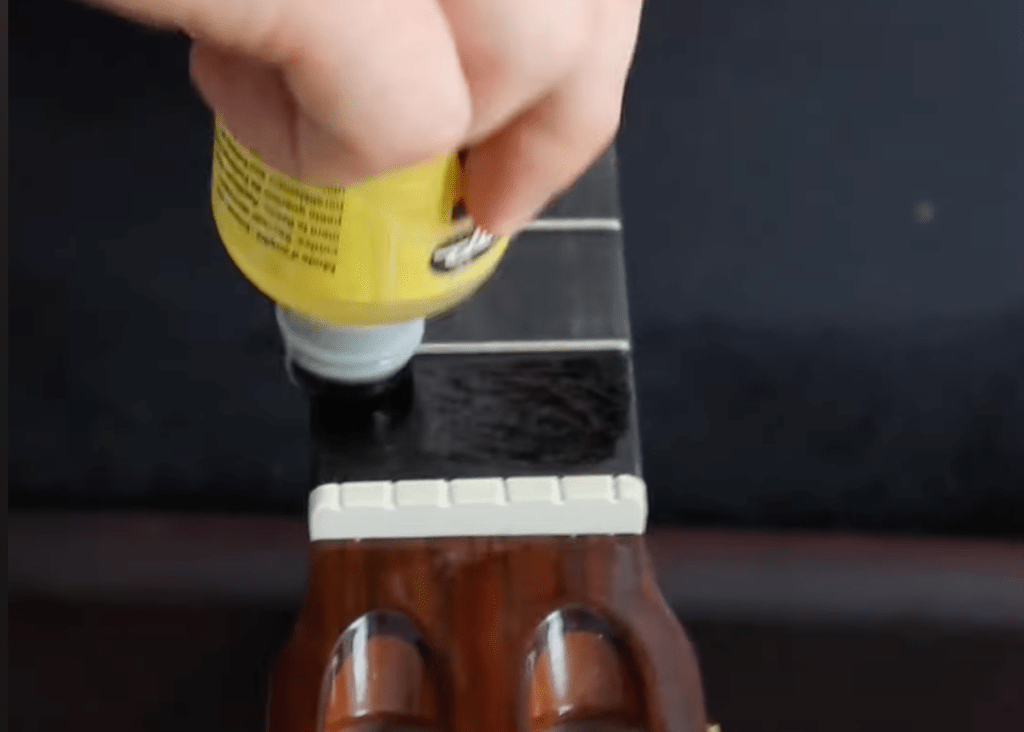 application de l'huile de citron sur la touche de guitare