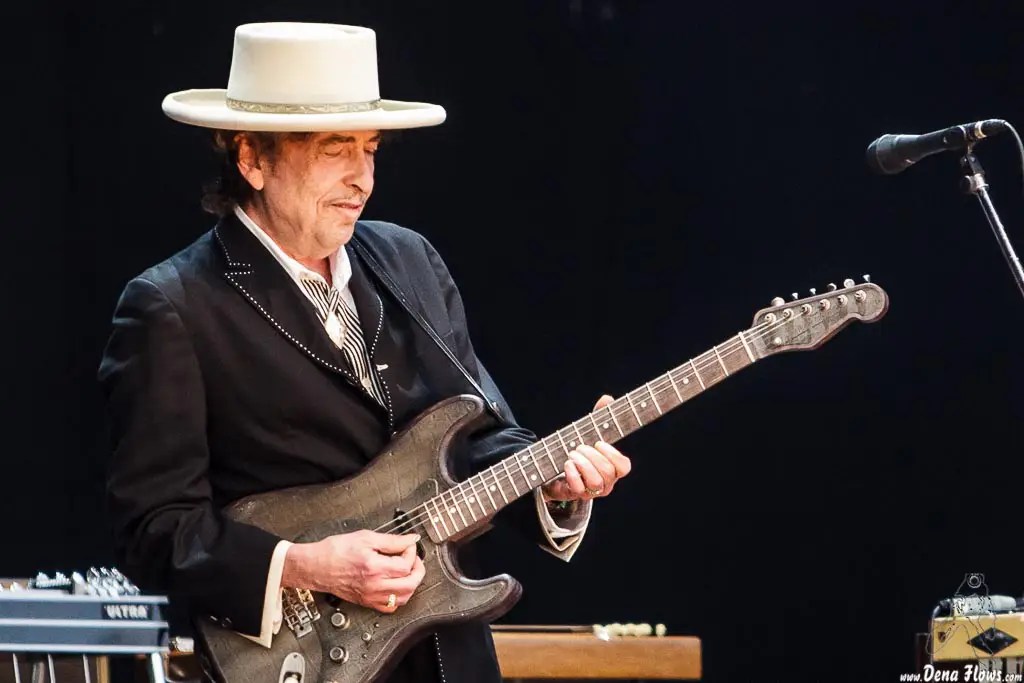 bob dylan sur scène avec un chapeau blanc qui joue de la guitare électrique