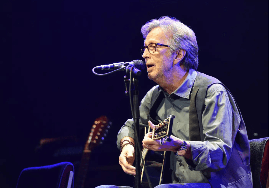 Eric Clapton jouant de la guitare acoustique, assis
