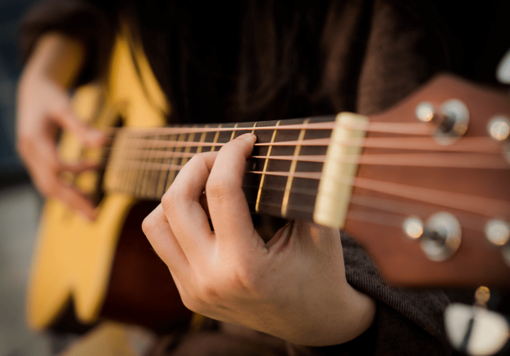 main qui effectue un accord sur le manche d'une guitare accoustique
