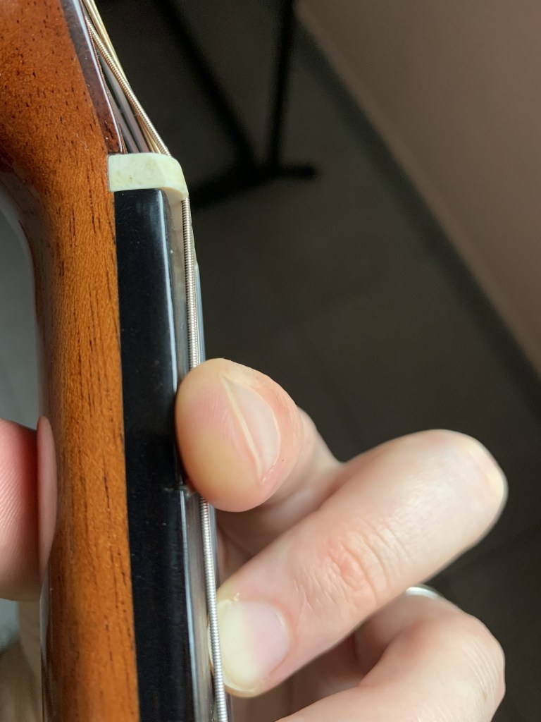 manche de guitare vu du dessus avec position de l'index en accord barré de FA majeur